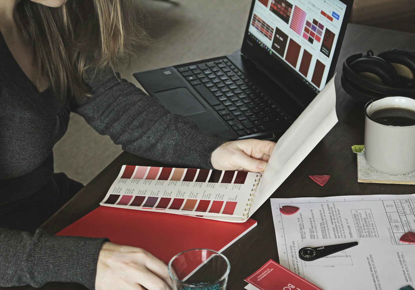 Projektant przegląda wzorniki kolorów na laptopie i w książce.