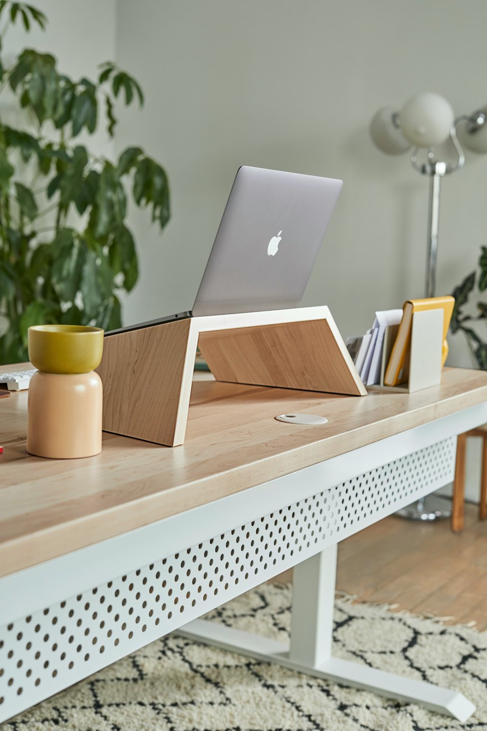 Laptop na jasnym drewnianym stojaku na nowoczesnym biurku.
